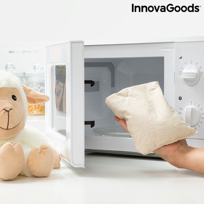 Sheep Soft Toy with Warming and Cooling Effect Wooly InnovaGoods next to a microwave holding a warming pouch.