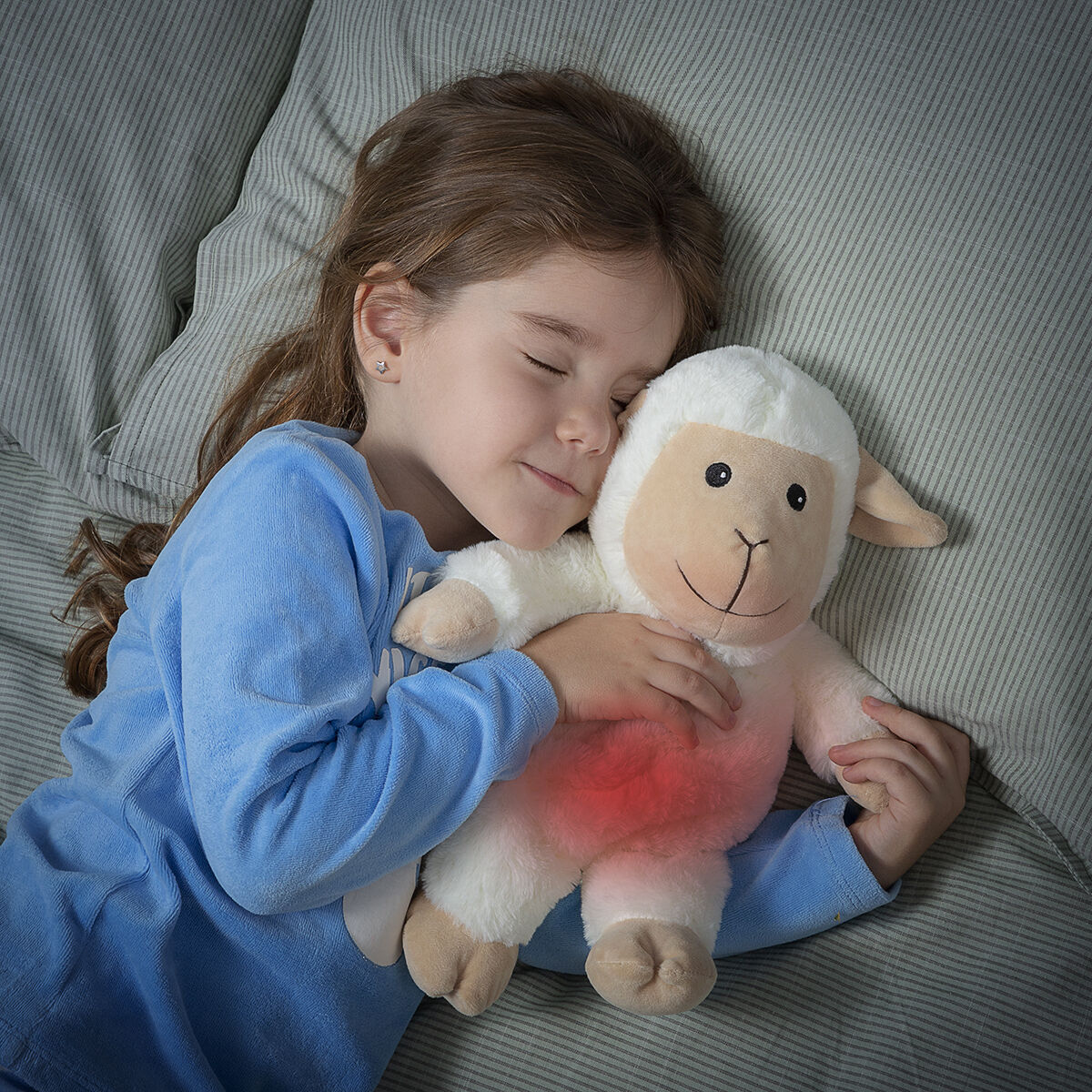 Child sleeping peacefully with Sheep Soft Toy with Warming and Cooling Effect Wooly InnovaGoods in her arms.